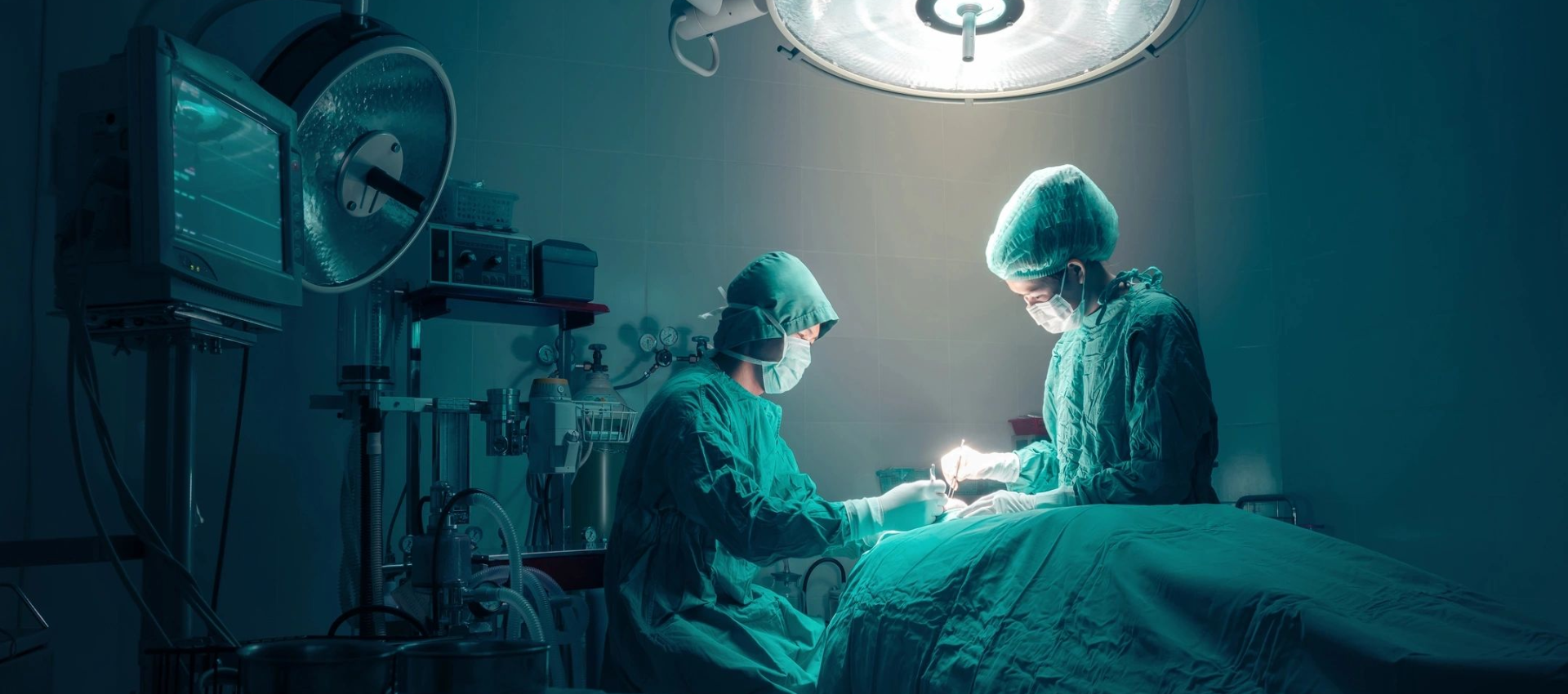 Two board-certified orthopedic surgeons operate on a patient in a surgical room under bright overhead lights.